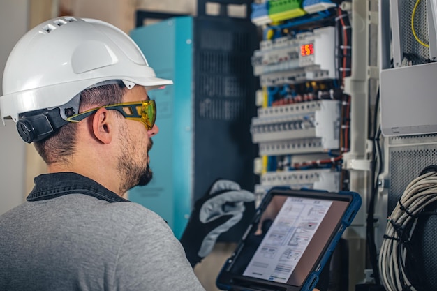 Man een elektrische technicus die werkt in een schakelbord met zekeringen