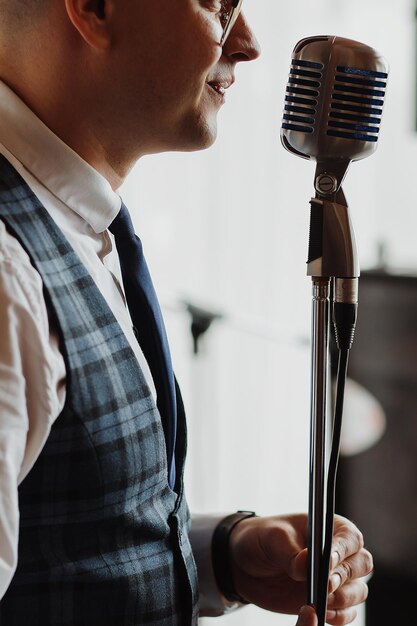 Man in elegant black jacket and blue shirt singing