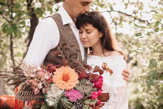 A man embraces a girl with a bouquet in her hands. Gentle embrace of lovers