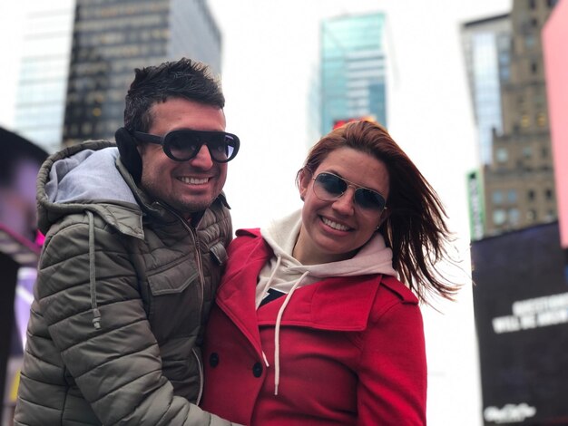 Photo man embracing woman against buildings and sky