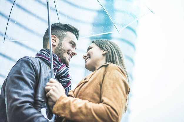 Foto uomo che abbraccia una donna mentre la donna tiene un ombrello