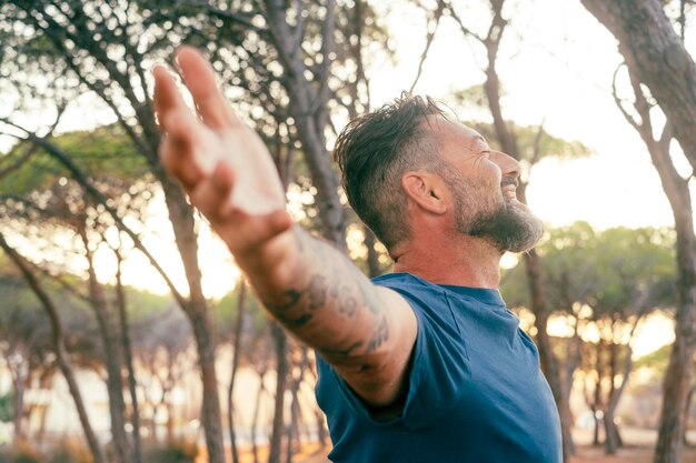 Photo man emotion happiness and freedom lifestyle opening arms in outdoor leisure activity with forest park in background and sunset light travel overjoyed male people living moment outside wellbeing