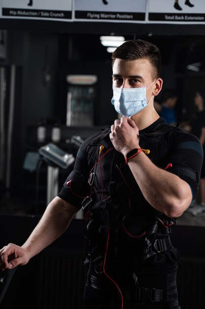 Man in EMS suit and medical mask in gym