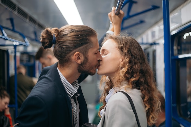 Man en een verliefde vrouw kussen elkaar in een metro.