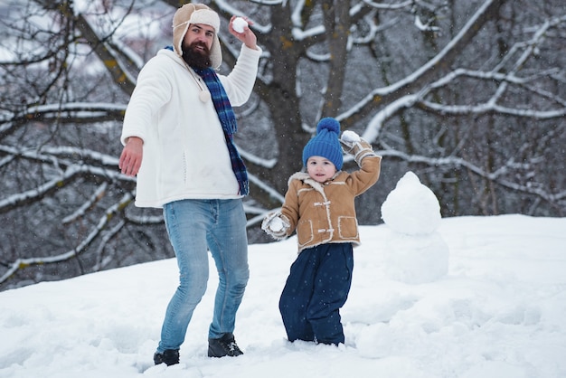 man en kleine jongen die een sneeuwpop buiten maken