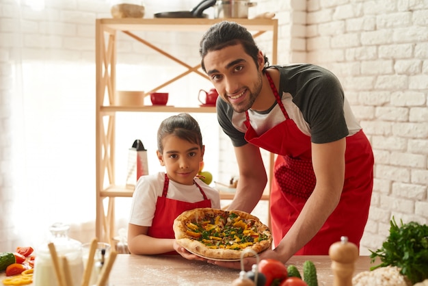 Man en meisje gekookte pizza op keuken