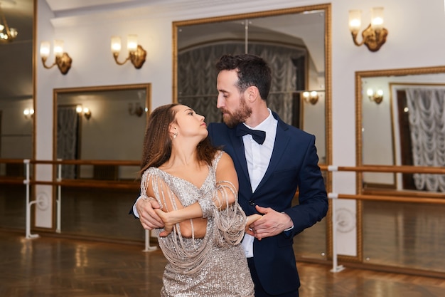 Man en vrouw dansen en kijken elkaar aan in een vintage hal met spiegels