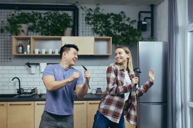 Man en vrouw dansen samen plezier thuis in de keuken een multiraciale familie