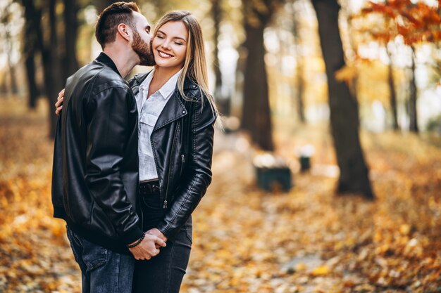 Man en vrouw die en in de herfstpark koesteren glimlachen.