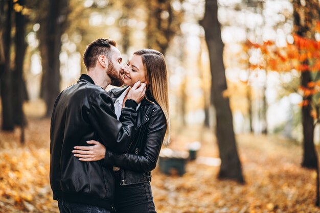 Man en vrouw die en op de achtergrond van de herfstpark koesteren glimlachen.