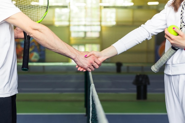 Man en vrouw die handen schudden bij tennisbaanclose-up Horizontale foto