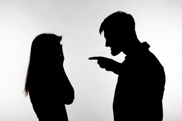 Man en vrouw die huiselijk geweld uiten in studio silhouet geïsoleerd op een witte achtergrond.