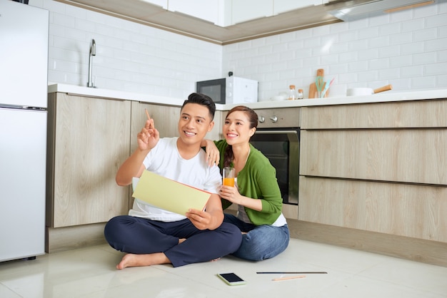 Man en vrouw die hun huisplannen bekijken die in hun nieuwe huis zitten