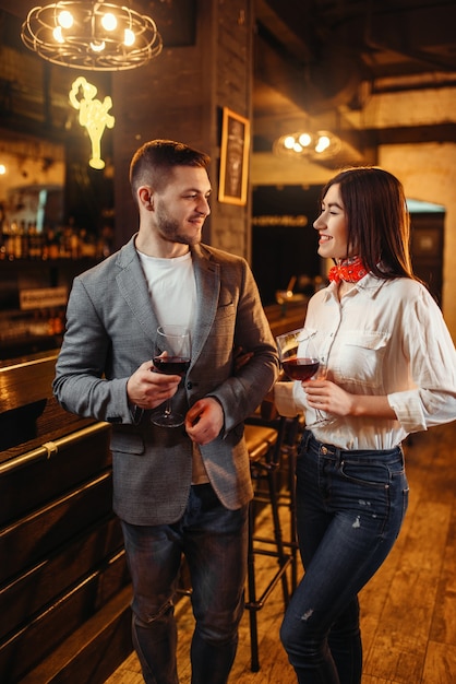 Man en vrouw drinkt rode wijn aan toog