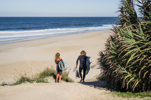 man en vrouw gaan naar de oceaan met surfplanken. man en meisje gaan surfen