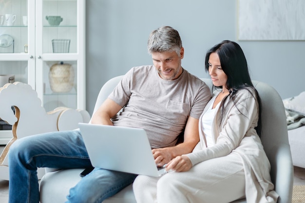 Man en vrouw gebruiken een laptop in hun woonkamer