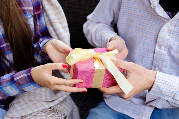 Man en vrouw handen met een roze geschenkdoos.