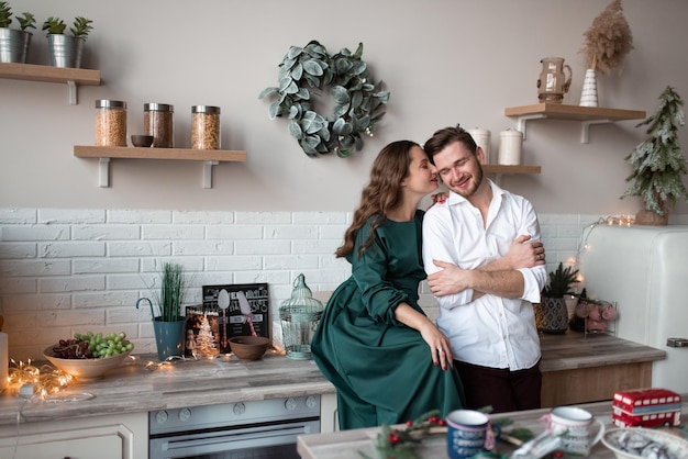 Man en vrouw hebben samen plezier in een keuken in scandinavische stijl de keuken is versierd voor kerstmis de vrouw kust haar geliefde op de wang