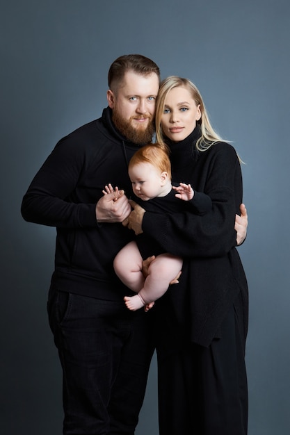 Man en vrouw houden een baby in hun armen. Portret van een getrouwd stel na de geboorte van een kind. jong gezin