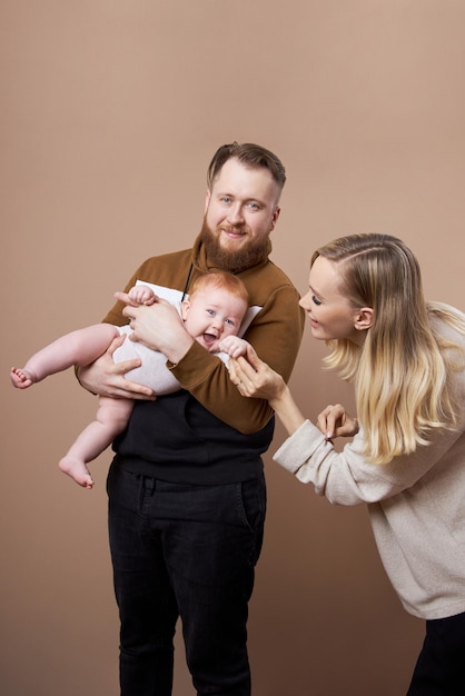 Man en vrouw houden een baby in hun armen. Portret van een getrouwd stel na de geboorte van een kind. jong gezin