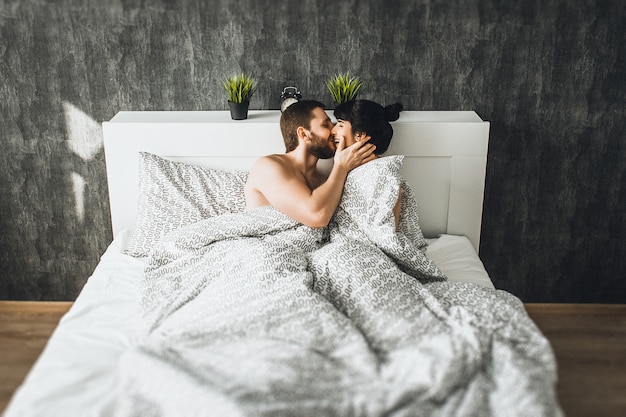 Man en vrouw in bed. jongen en meisje hebben seks. verliefde paar in bed. huwelijksnacht. pasgetrouwden kussen. de liefde bedrijven. liefhebbers in bed afbeelding foto