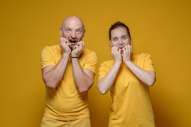 Man en vrouw in de gele T-shirts zijn geschokt, ze kijken met angstige ogen