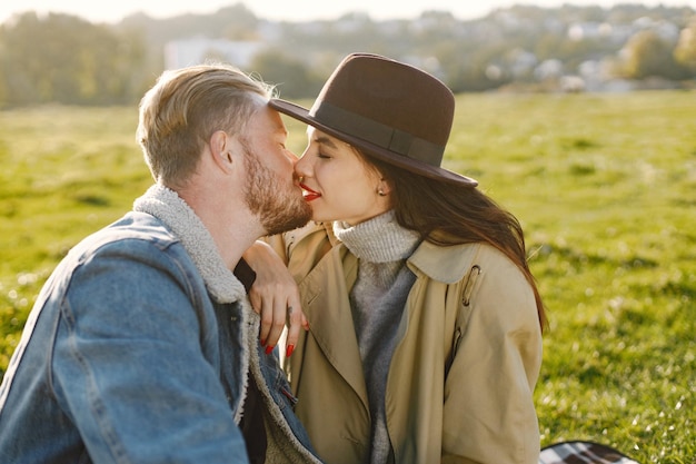 Man en vrouw in mode kleding zittend op een natuur op een picknickkleed. Man met jas en vrouw jas