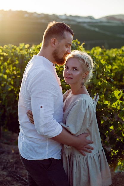 Man en vrouw in witte kleren staan bij zonsondergang in een druivenveld