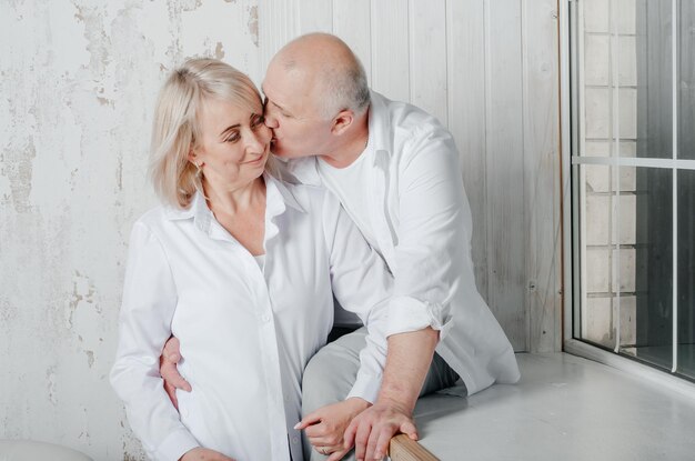 man en vrouw in witte overhemden knuffelen en kussen