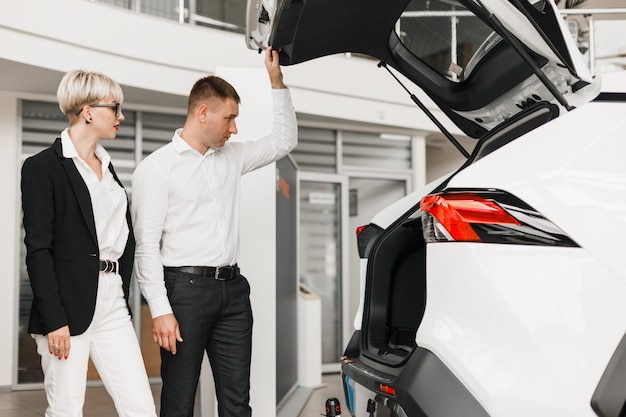 Man en vrouw kiezen een auto in de dealer.