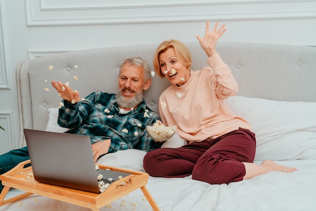 Man en vrouw kijken een film op het bed en eten popcorn