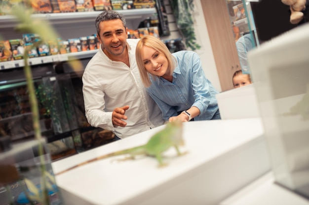 Man en vrouw kijken naar leguaan tijdens een bezoek aan de dierenwinkel