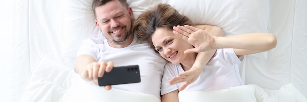 Man en vrouw liggen in bed en nemen selfie bovenaanzicht online communicatie op afstand concept