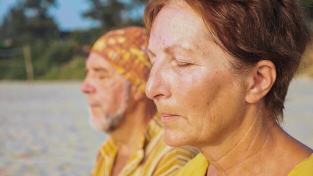 Man en vrouw mediteren terwijl ze op het strand zitten