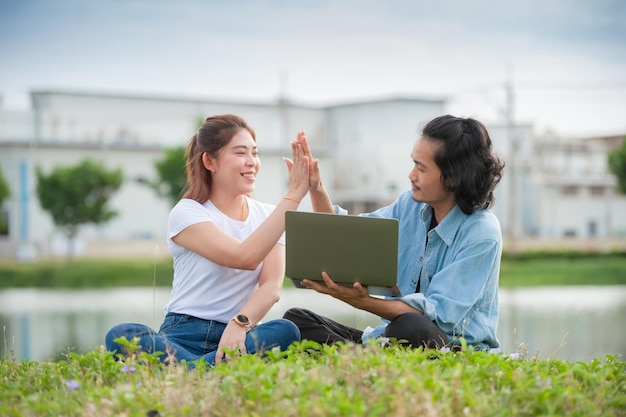 Foto man en vrouw met behulp van laptopcomputer buiten zitten