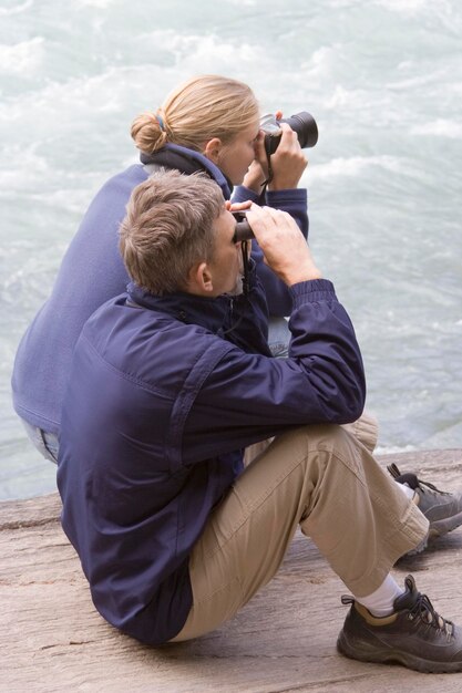 Foto man en vrouw met een camera met een verrekijker bij de rivier