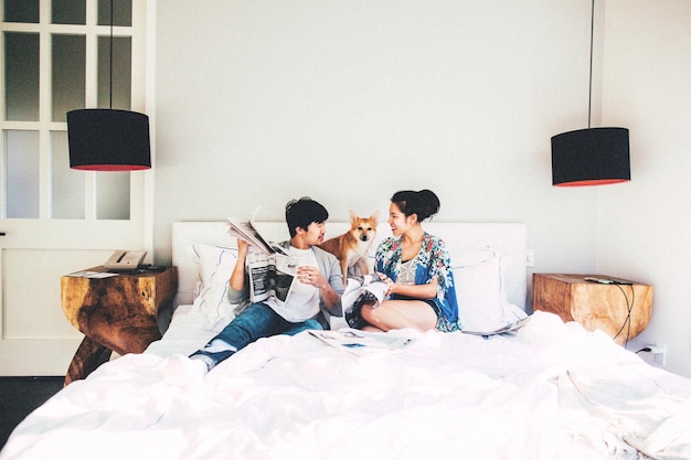 Man en vrouw met krant zitten bij hond op bed thuis