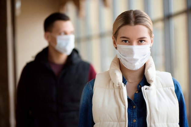 man en vrouw met medisch gezichtsmasker in luchthaven