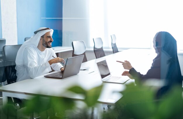 Man en vrouw met traditionele kleding aan het werk in een kantoor in Dubai