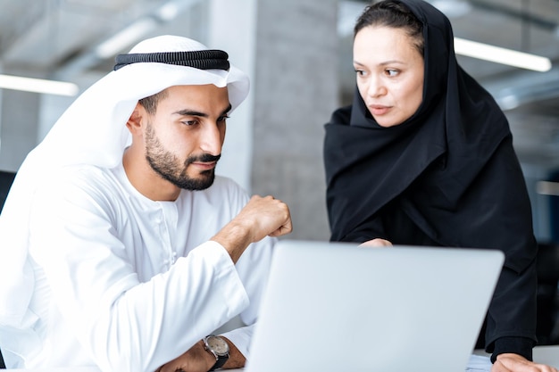 Man en vrouw met traditionele kleding aan het werk in een kantoor in Dubai