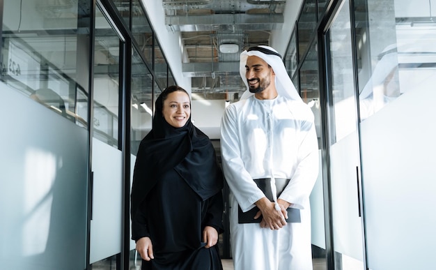 Man en vrouw met traditionele kleding uit de Emiraten werken in een kantoor in Dubai