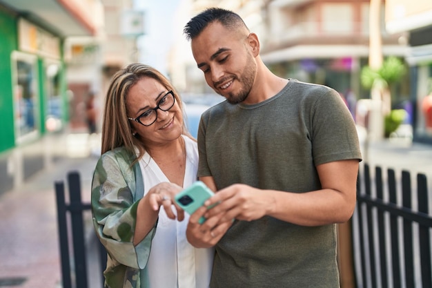 Man en vrouw moeder en dochter met behulp van smartphone op straat