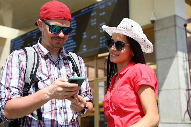 Man en vrouw naast een informatiebord en kijken naar het smartphonescherm