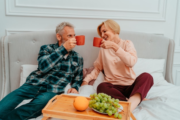 Man en vrouw ontbijten op bed met koffie en fruit