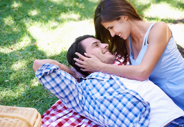 Man en vrouw ontspannen zich in het park voor een picknick op vakantie voor de zomer bonding gelukkig of buiten koppel glimlachen en omhelzen op de deken op het gras voor valentijnsdag of dating verbinding of rust liefde of weekend