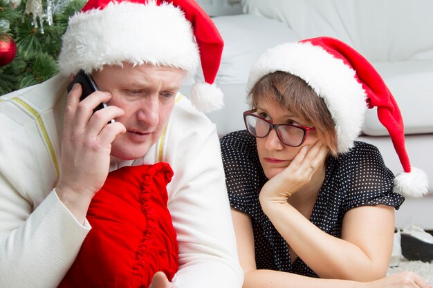 Man en vrouw op oudejaarsavond problemen met kerstmis een man met een mobiele telefoon en een bezorgde vrouw