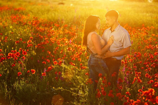 Man en vrouw op papavergebied bij romantische zonsondergang ,.