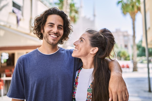 Man en vrouw paar glimlachend zelfverzekerd knuffelen elkaar op straat