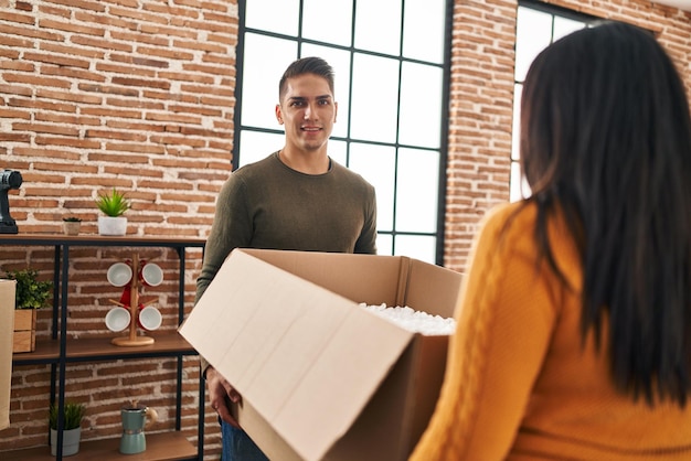 Man en vrouw paar lachend zelfverzekerd pakket bij nieuw huis