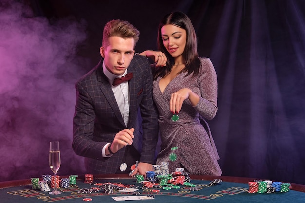 Man en vrouw pokeren in casino vieren overwinning aan tafel met stapels chips geldkaarten cham